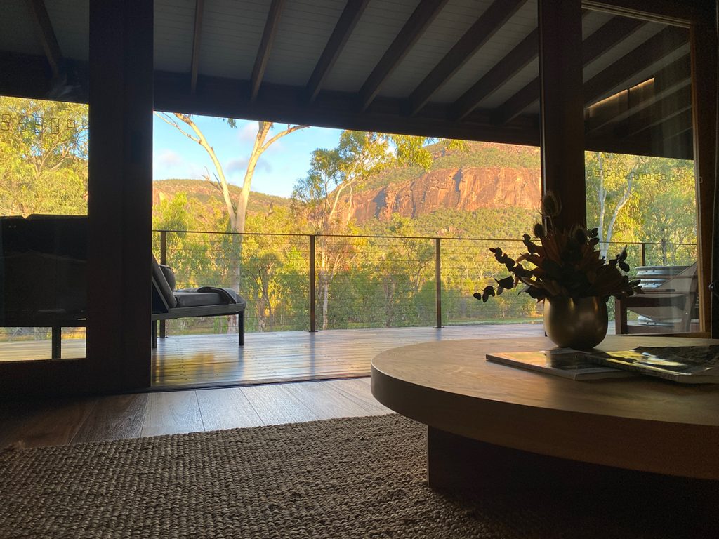 Interior view of a room at Mount Mulligan Lodge with balcony and mountains in the background.